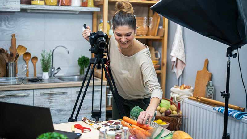 A woman in her kitchen creating a food vlog.