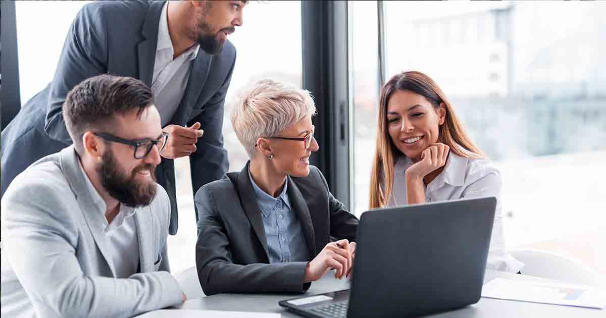 Business people gathered around a computer in an office.